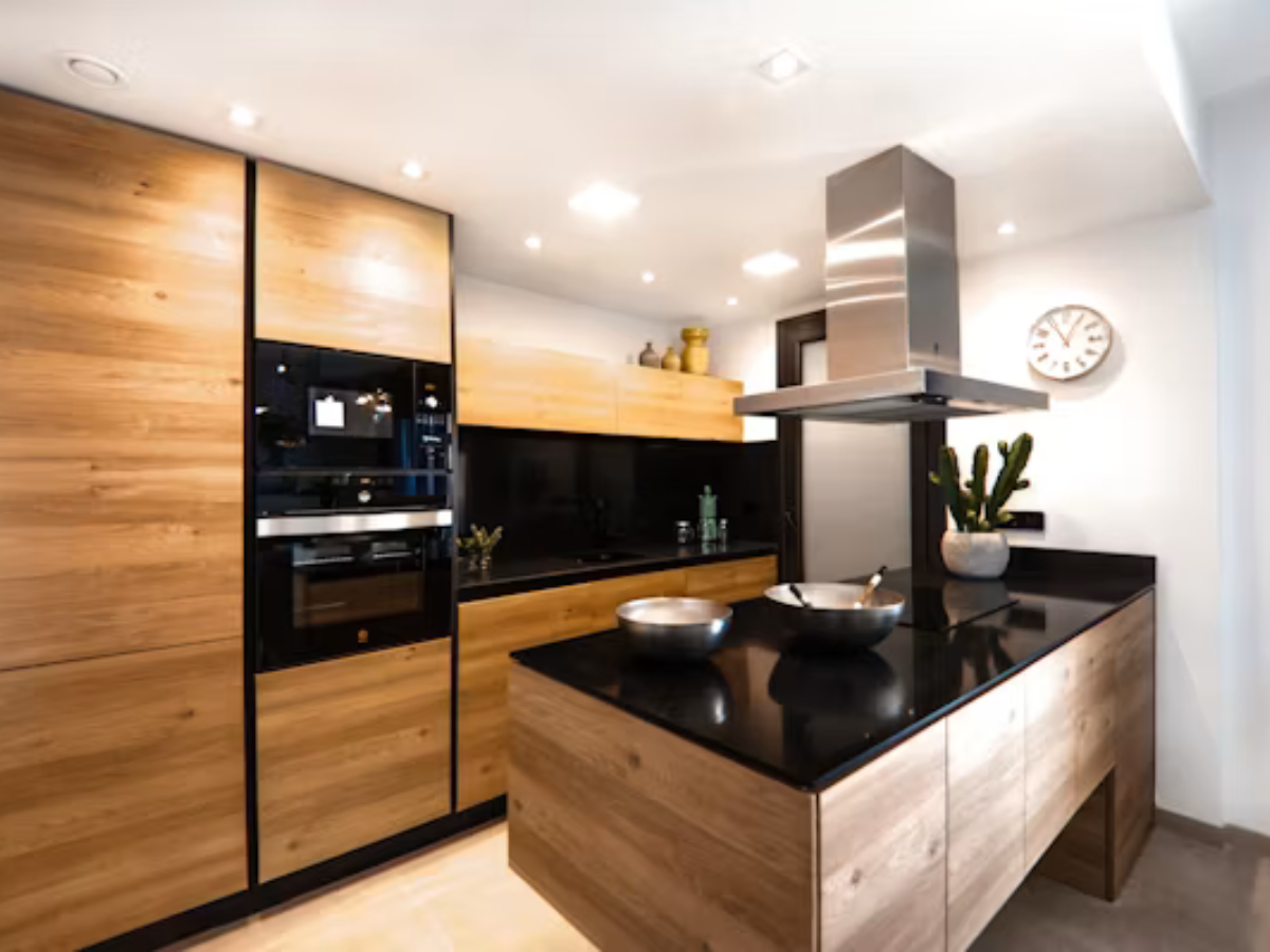Grey modular kitchen with wooden countertop and hanging utensils by Splendid Interio