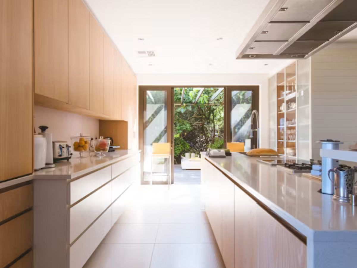 Light wood galley modular kitchen with island and garden view by Splendid Interio