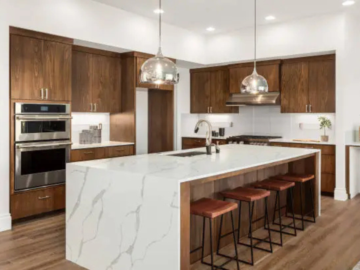 Walnut wood modular kitchen with white marble waterfall island by Splendid Interio